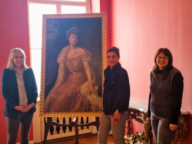 Bild 1 Lara Klewin (Mitarbeiterin), Anke Schilling (Ausstellungskoordinatorin) und Ina Klemm (Geschäftsführerin Tourismus und Sport GmbH) mit dem Portrait der Fürstin Eleonore von Schönburg-Waldenburg.